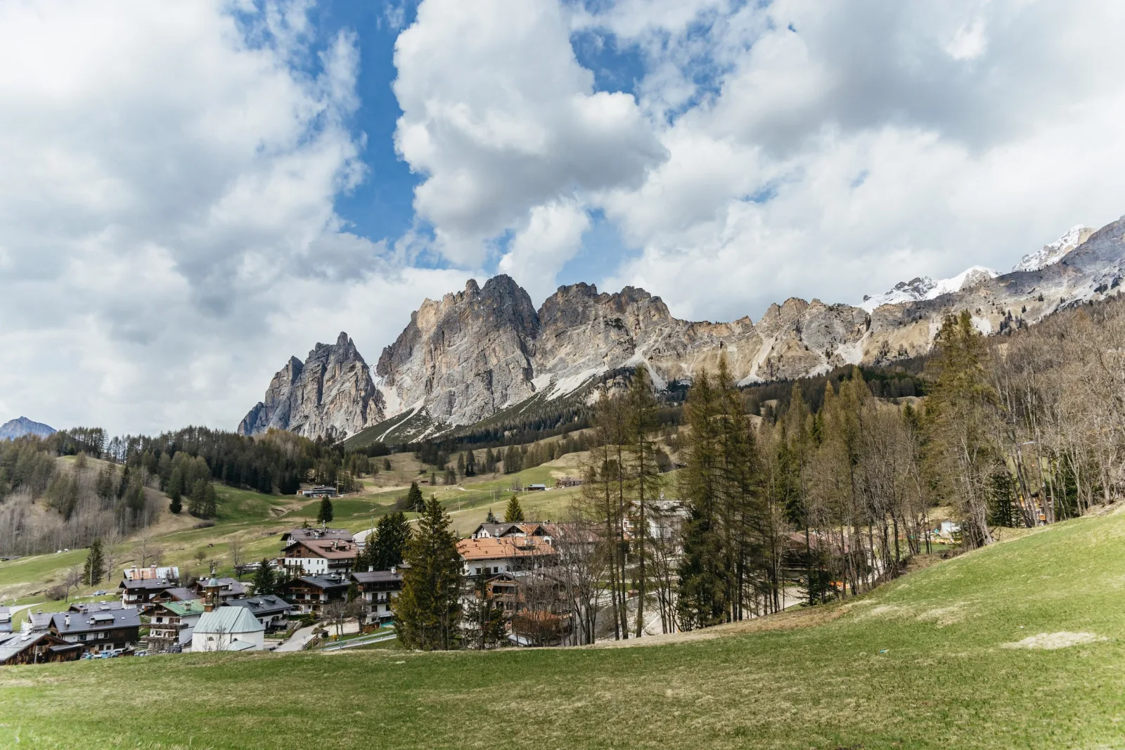 Mountain village of wooden houses below a serrated Dolomite ridge in early spring