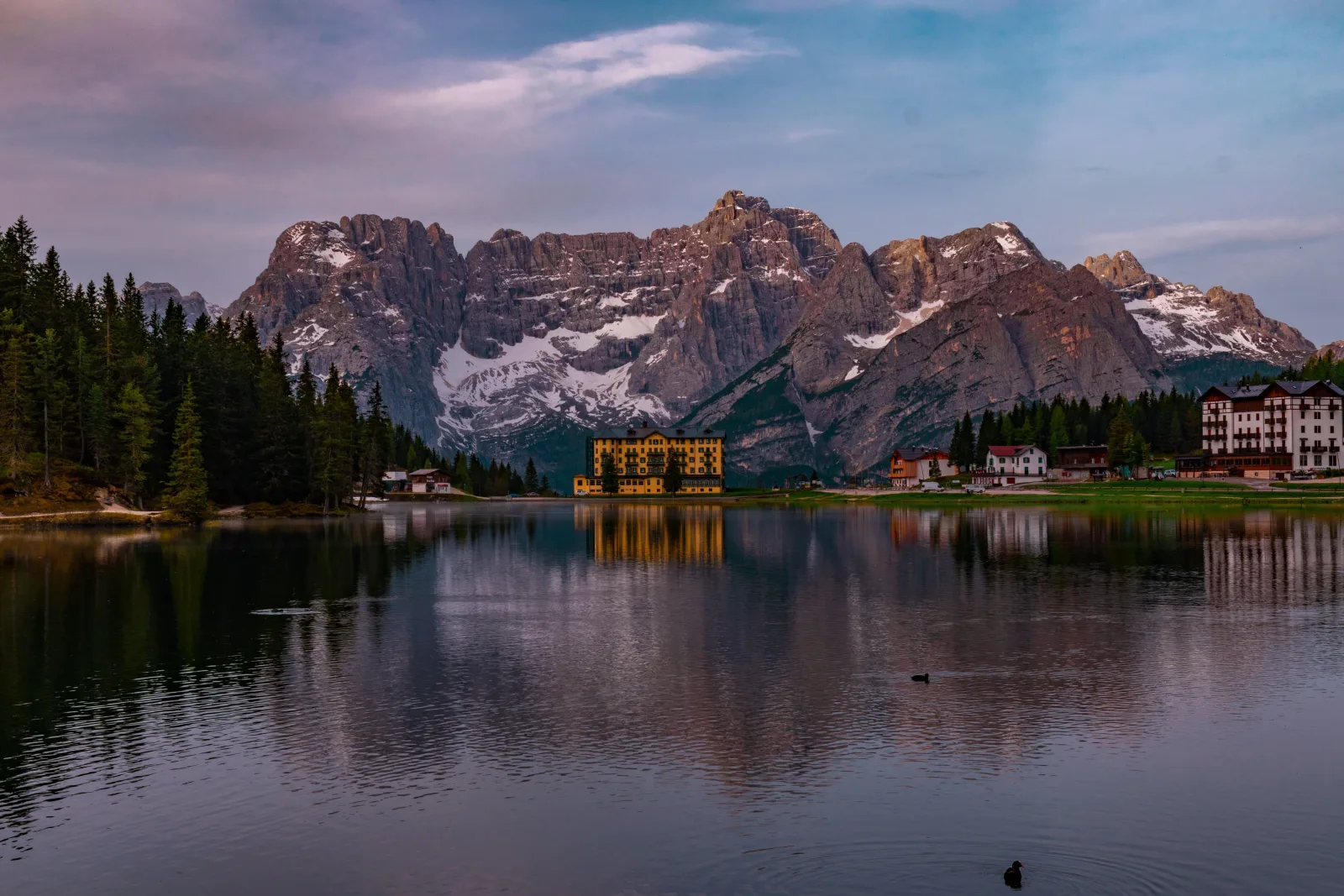 Lake Misurina at dusk with the lakeside hotel lit and the Sorapiss peaks reflected in still water