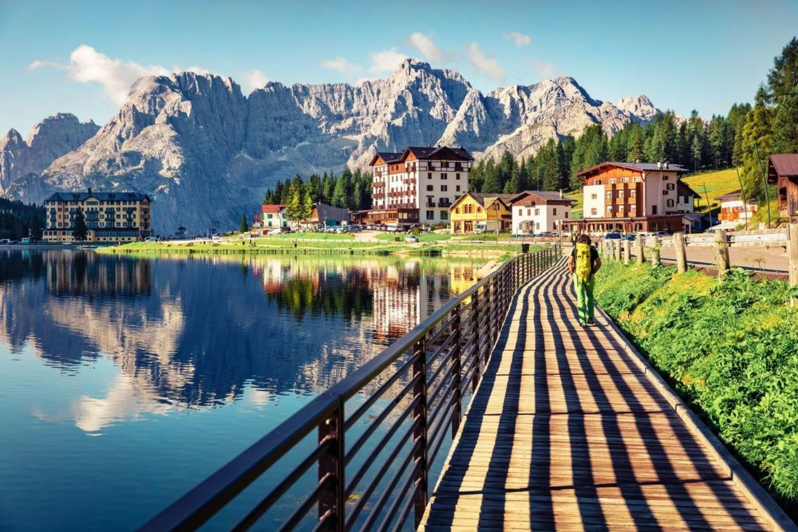 Wooden boardwalk running along the edge of Lake Misurina with peaks reflected in still water