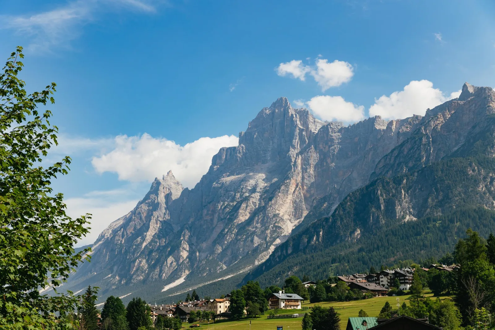 Jagged Dolomite peaks rising above the wooded Cortina valley under a blue sky