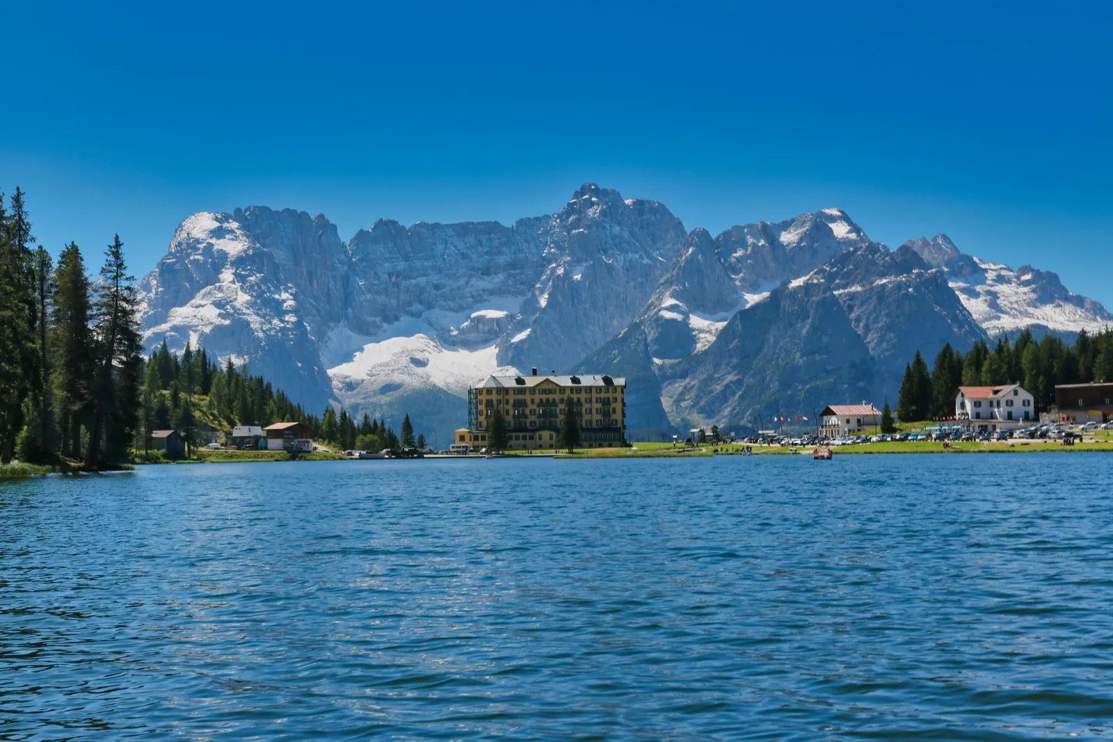 Lake Misurina's blue water with the Grand Hotel on the shore and the snow-streaked Sorapiss group behind