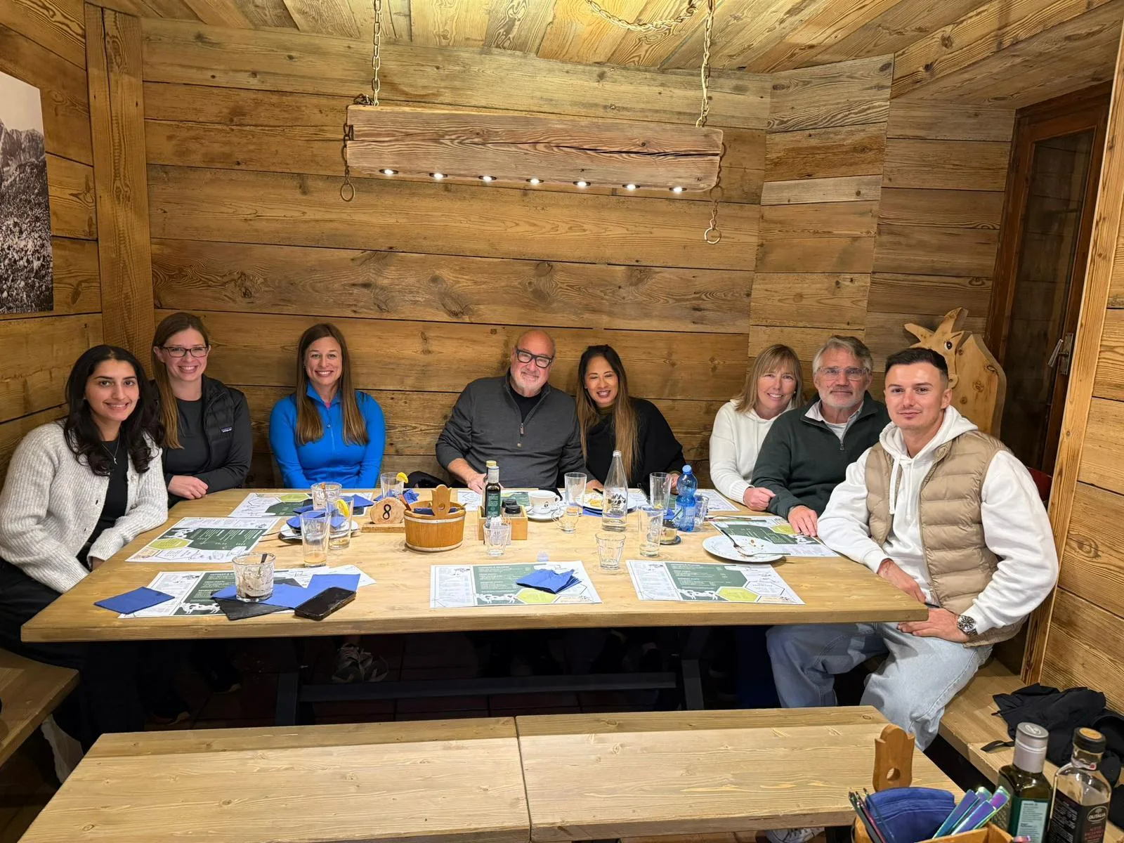 Tour group seated at a long wooden table inside a traditional Dolomites mountain restaurant