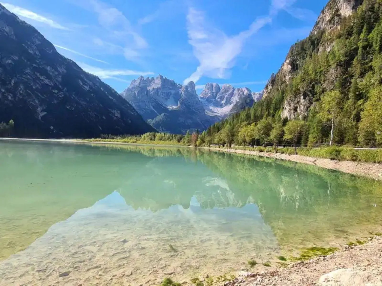 The clear shallow green water of Lake Landro with Dolomite peaks reflected at the far end