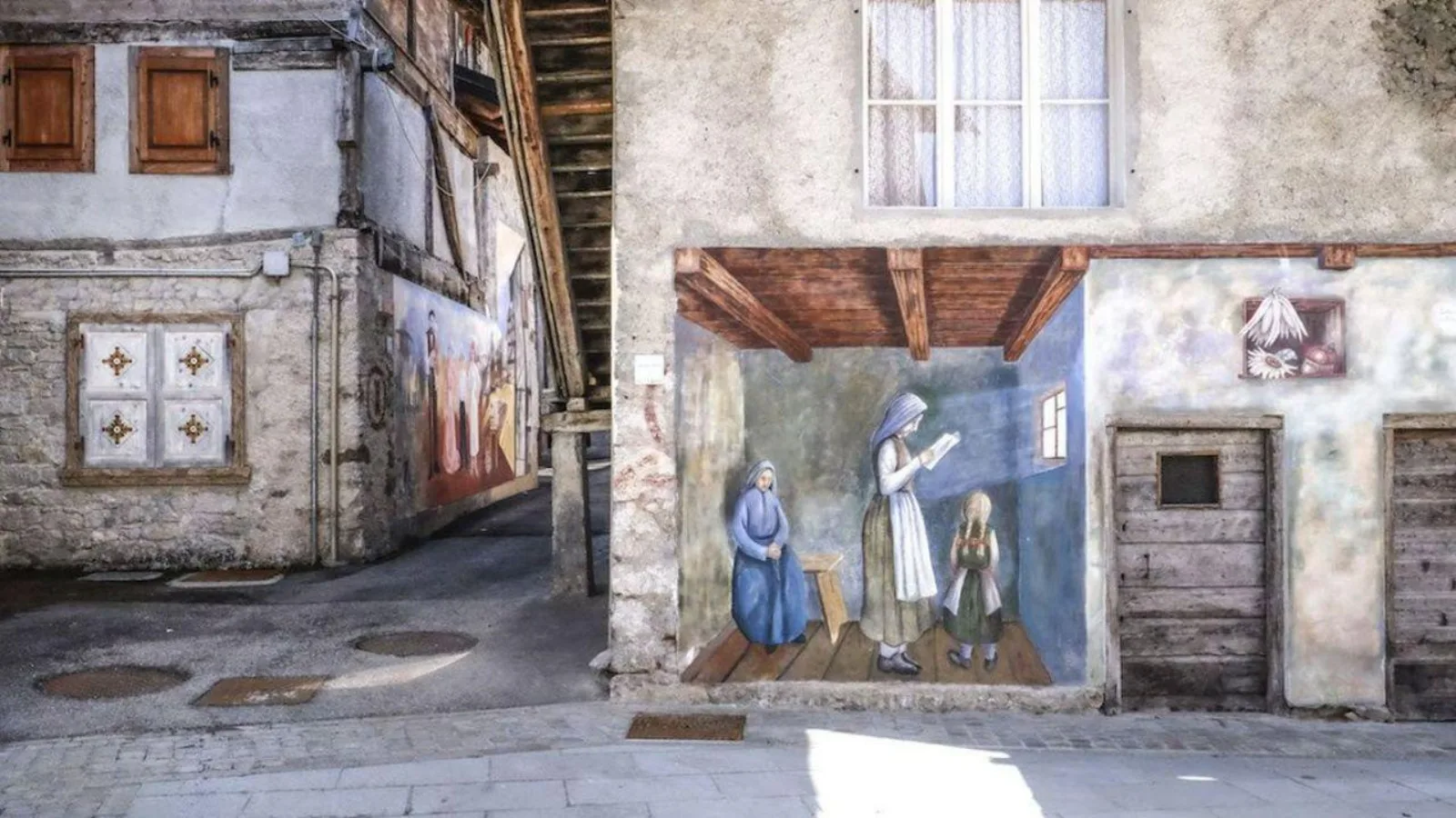 Painted mural of women in traditional dress on a village house wall in Cibiana di Cadore
