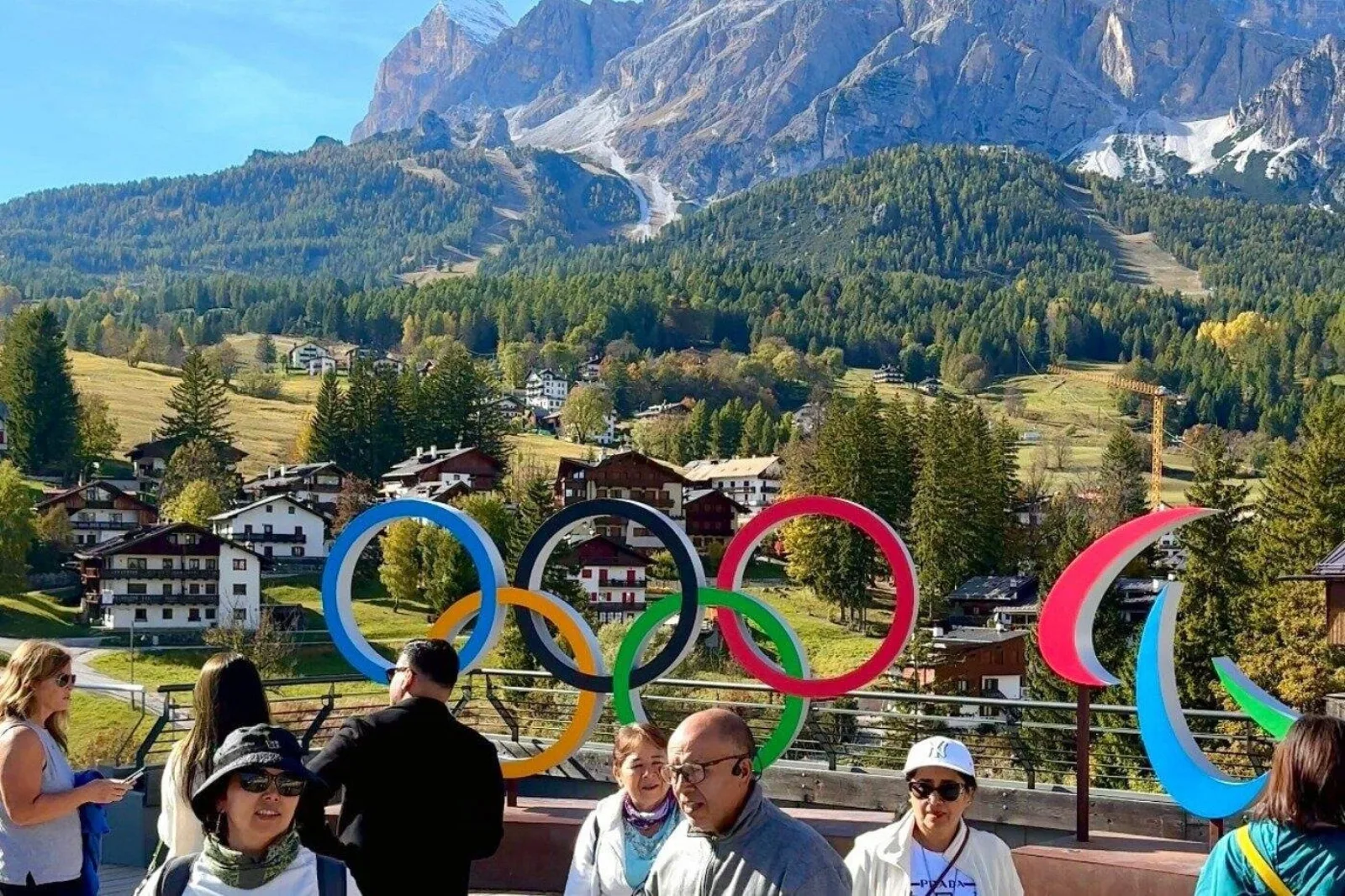 Tour group gathered at the Olympic rings above Cortina d'Ampezzo with the green valley beyond
