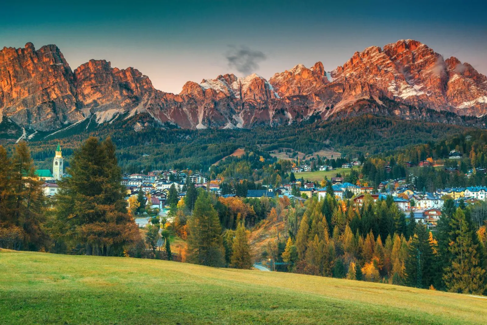 Cortina d'Ampezzo from above at sunset, the Cristallo massif lit orange over the town